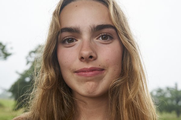 Alice a young white woman with long dark blonde hair and big luscious bushy eyebrows set above big brown eyes. She is wearing a big toothy smile showing she will not be intimidated by a fight with big food.