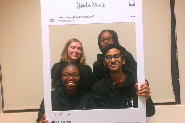 A group of 4 youth activists posing in a cardboard Instagram style frame that says 'Peterborough Youth Council' and 'Youth Power'.