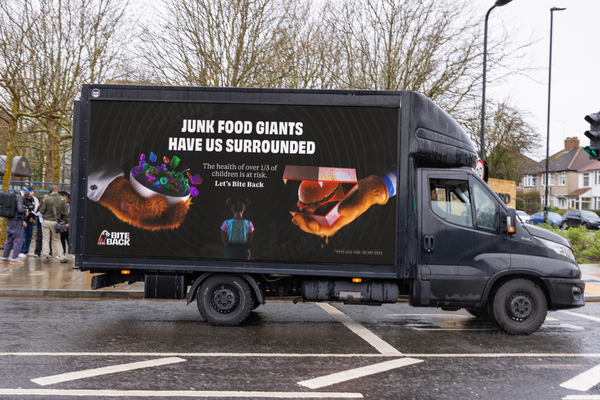 A digivan parked in front of the Ferrero head quarters showing the Ferrero sign. On the screen is displayed our billboard. A small child sitting in the middle and hands looming over the child with burgers and sugary cereal. It carries the message "Fuel Us Don't Fool Us"