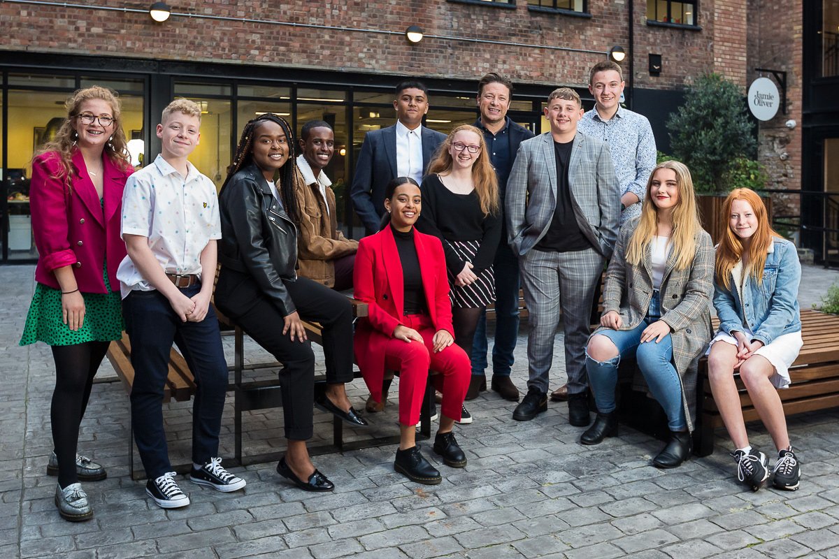 Bite Back's Youth Board in 2019: eleven teenagers stand in a courtyard together with chef Jamie Oliver.